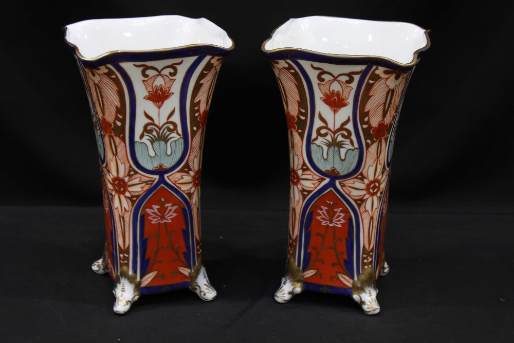 A pair of modern porcelain vases, of square section with flared rims raised on four scrolled feet,