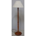 A modern stained beech turned standard lamp with cream shade.