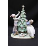 A Lladro porcelain figure group of two children dressing a Christmas tree, 34cm high.