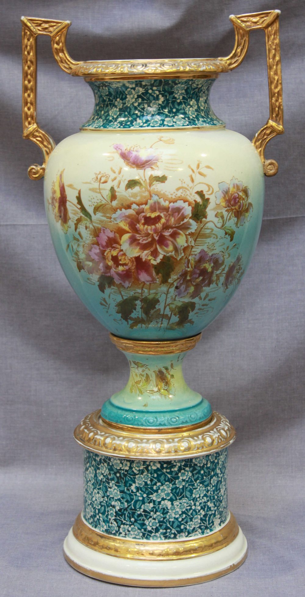 A large Edwardian pottery pedestal vase with gilded and printed floral decoration, 60cm high.