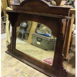An Edwardian stained walnut overmantel mirror, with arched pediment, raised shelf above a shaped