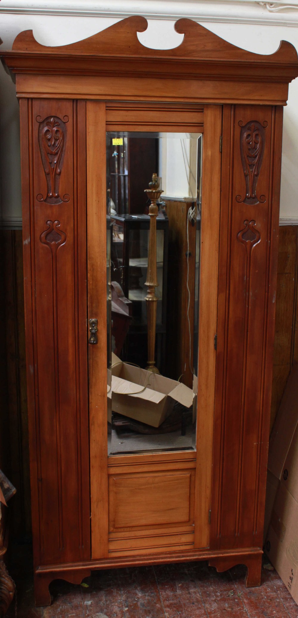 An Edwardian stained walnut single-door wardrobe, with scroll-shaped cornice above a single mirrored