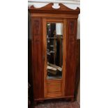 An Edwardian stained walnut single-door wardrobe, with scroll-shaped cornice above a single mirrored