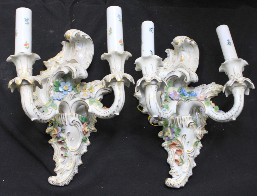 A pair of Dresden porcelain twin-light wall sconces modelled in the rococo style and encrusted