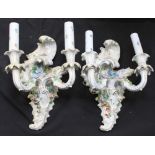 A pair of Dresden porcelain twin-light wall sconces modelled in the rococo style and encrusted