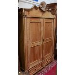 A 19th century continental stripped pine double door wardrobe, with scroll-carved and moulded