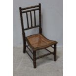 A stained beech wood bobbin turned chair, with rattan caned curved seat.