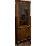 A reproduction mahogany corner display cabinet with dentil cornice above three shelves enclosed by