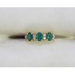 A 14ct gold bridge ring claw set with three emeralds and eight small diamonds, approx. total