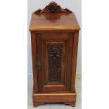 An Edwardian stained walnut bedside pot cupboard with carved and shaped raised back, foliate