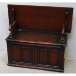 An oak 20th Century monk’s bench with hinged back, the box seat with carved and panelled front on