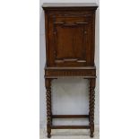 A stained oak cupboard on stand, in the 17th century style, single panel door enclosing shelves,