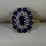 An 18ct gold sapphire and diamond cluster ring claw set with a central sapphire surrounded by a