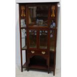 An Art Nouveau stained mahogany display cabinet, with plain beveled cornice, inverted glazed front
