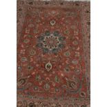 A Persian Isfahan style rug, with central motif surrounded by a flower strewn peach ground and a