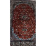 An Oriental hand knotted wool and silk rug with central medallion on a red ground and multiple