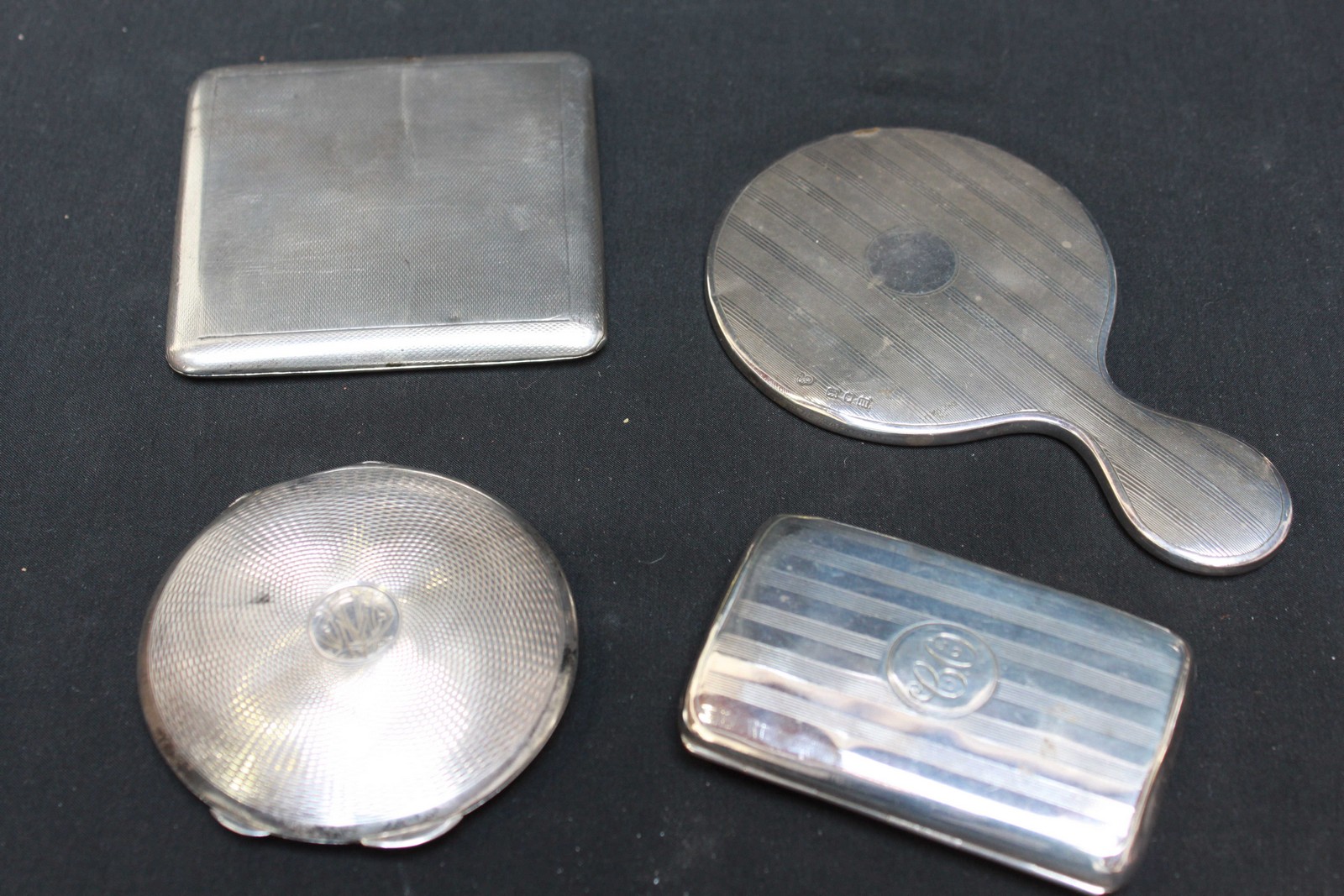 Two silver cigarette cases; a silver compact; and a miniature silver hand mirror. Weighable silver