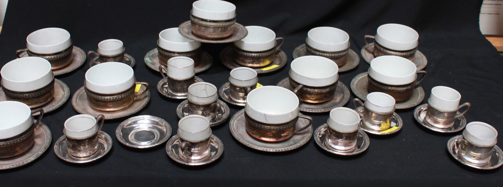 A large set of Continental silver and saucers with white porcelain liners, decorated with a band