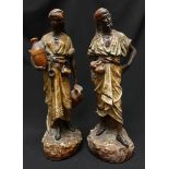 A pair of cast plaster figures of an Arabic man and woman, on rocky naturalistic bases. 51 cm high.