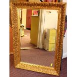 A modern mirror of rectangular form with bevelled glass in flower and wheat-sheaf moulded frame,