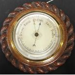 An early 20th century aneroid barometer, with silvered dial and thermometer, in stained oak rope-