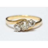 An 18ct three stone crossover diamond ring claw set with round brilliant cut diamonds, the