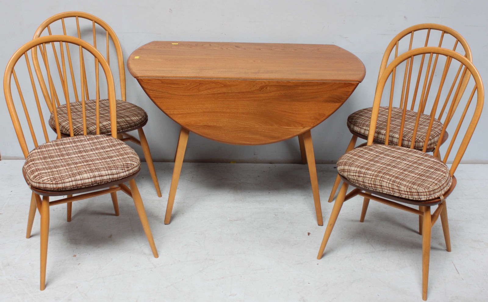 A 20th Century light elm 'Ercol', oval kitchen dining table with two D-shaped drop leaves and raised