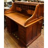 An early 20th Century oak roll-top desk, opening to reveal a fitted interior with drawers and pigeon