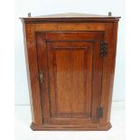 An oak hanging corner cupboard with single panelled door enclosing two shelves, 90cm.