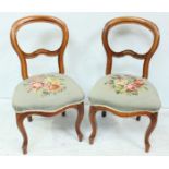 A pair of Victorian stained walnut balloon back standard chairs with floral tapestry seats on