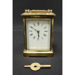An early 20th century brass carriage clock, with white enamel dial and black Roman numerals, with