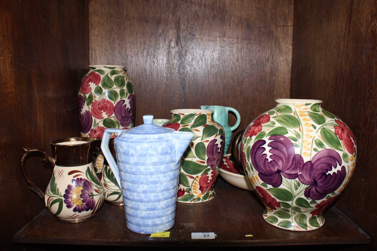 SECTION 53. A shelf of assorted Wade pottery jugs and vases, decorated with flowers and leaves.