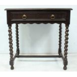An oak side table with long central frieze drawer and shaped apron, raised on barley twist supports,