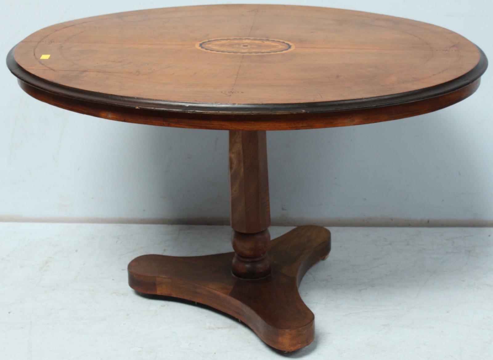 A Victorian walnut oval loo table, with central inlaid panel, supported on an octagonal column