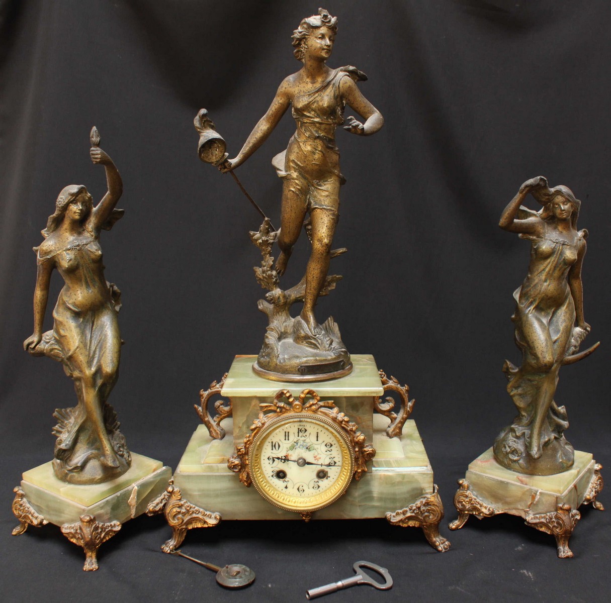 A French onyx and spelter figural clock garniture, formed as a classical lady stood atop an onyx