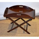A mahogany butlers oval tray, with hinged side flaps, on a folding stand. (Mid twentieth century.)