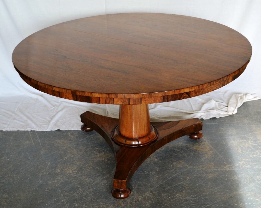 An early Victorian rosewood veneered loo table, the circular tilt top on a pillar stem with a