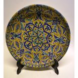 A Persian pottery charger blue, yellow and green, star design, the centre with a pomegranate and