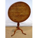A late eighteenth century oak occasional table, the circular tilt top on a slender vase turned