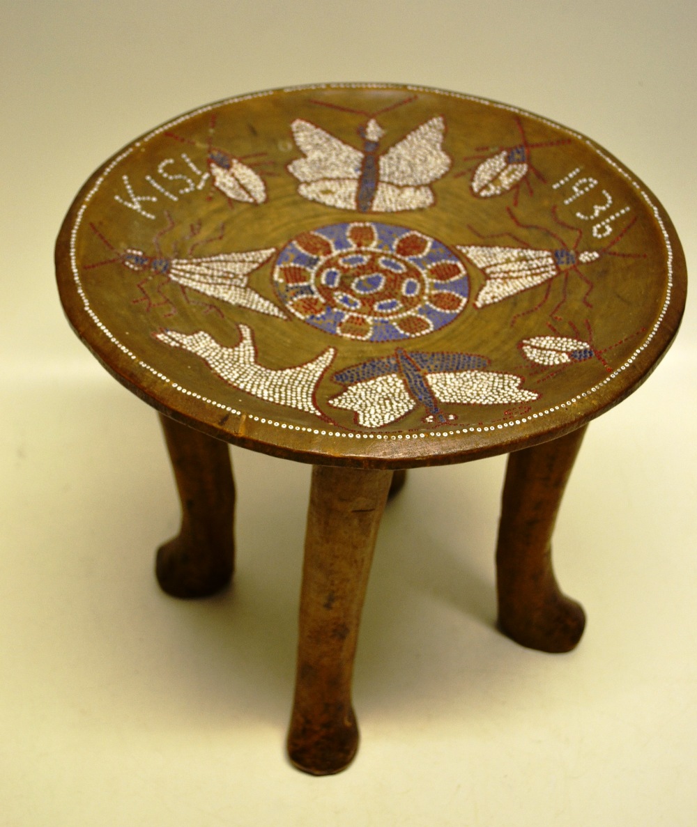 A Kenyan hardwood stool, the dish seat with red, white and blue beadwork of insects, butterflies and