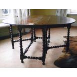 A large oak gateleg table, the oval drop leaf top on ball turned and block legs with stretchers,