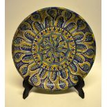 A Persian pottery blue yellow charger, the centre with a Catherine wheel, leaf and a flower head