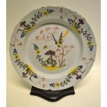 An eighteenth century Liverpool Delft dish, decorated in coloured enamels a pheasant perched on a