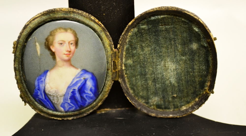 An eighteenth century enamel miniature portrait of a lady, wearing a blue over garment, a knotted