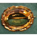 A large oval facetted citrine brooch, in a gilt metal scroll style setting, approx 4.5cms x 3.
