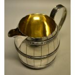 A late Victorian silver barrel milk jug, with a scroll spout, reeded coopering and scroll handle.