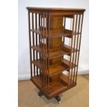 A late nineteenth century oak square revolving four tier bookcase, the shelves with vertical