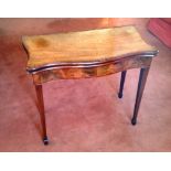 A Sheraton mahogany veneered serpentine front card table, the baize lined fold over flap top and