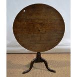An early nineteenth century oak occasional table, the circular tilt top on a vase turned stem with 3