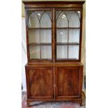 An Regency style mahogany bookcase, the cornice above adjustable shelves enclosed by a pair of